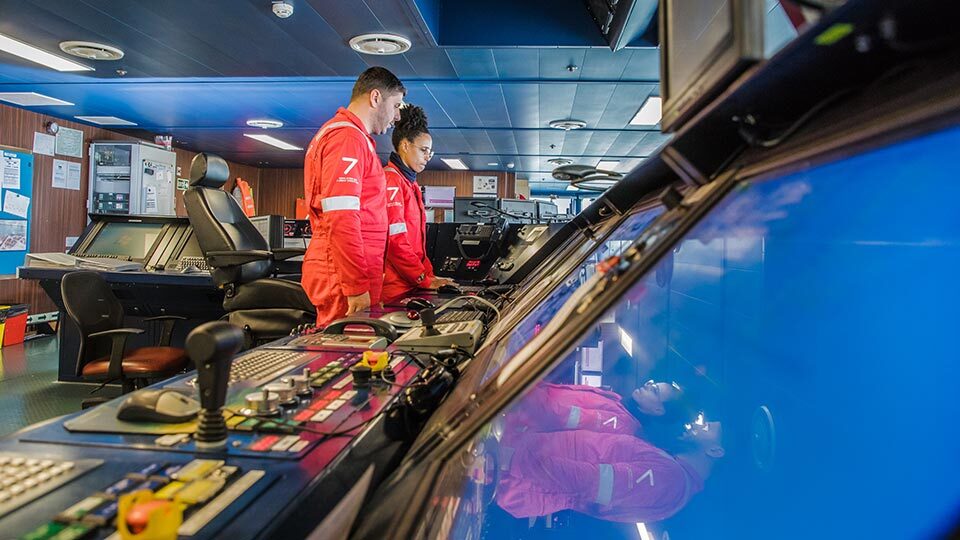 Crew at controls on vessel bridge